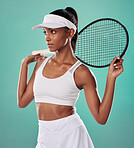 Stylish athlete or female tennis player holding a racket looking away and thinking against a green studio. Active African American sportswoman ready for sports competition or match in her sport
