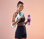 Active woman getting ready for routine fitness workout, holding yoga mat and bottle while standing against a pink studio background. Portrait of a fit female doing exercise, training and sports