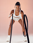 Exercise, fitness goals and active woman exercising with heavy battle ropes in a studio. Portrait of a serious and athletic female working out and doing weight training for a healthy and fit body