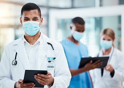 Buy stock photo A successful male doctor browsing the internet, using a tablet and wearing a mask inside a hospital. Portrait of a healthcare professional searching covid, flu or disease on a digital device 

