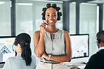 Friendly call center agent standing with arms crossed, looking proud and wearing a headset in an office with colleagues. Portrait of a smiling female customer service working looking confident