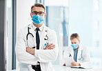 Doctor, physician or healthcare professional with covid face mask posing in hospital for medical health insurance background. Innovation, leadership and excellence male gp portrait with arms crossed