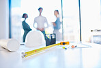 Measure tape on a table or desk in an architecture company office with engineer employee consulting in the background. Creative Engineering designer discuss building plans in a corporate business o