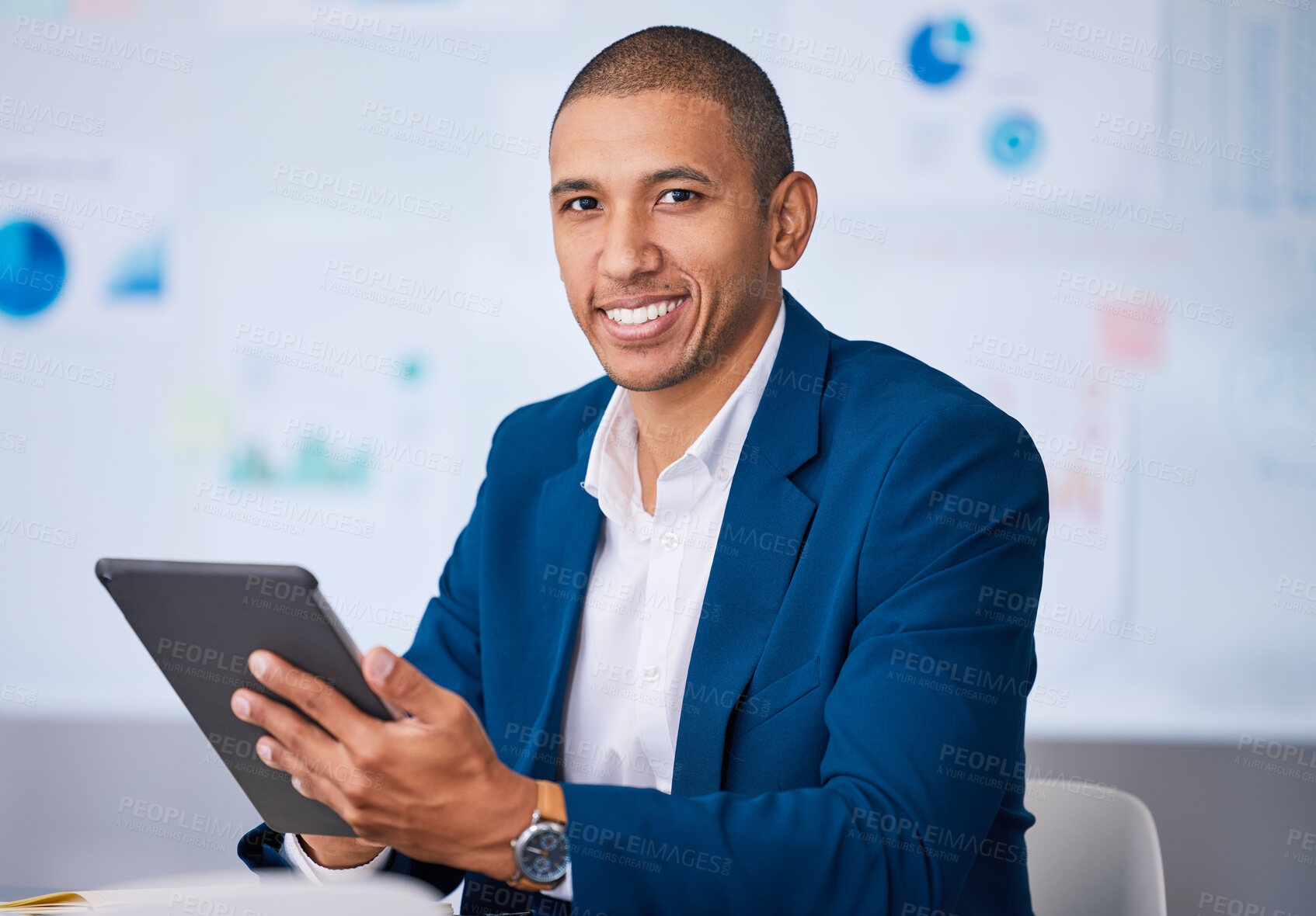 Buy stock photo Successful financial businessman smiling while browsing on a digital tablet in the office. Portrait of a male professional accountant feeling positive after completing a deal or finishing a work task