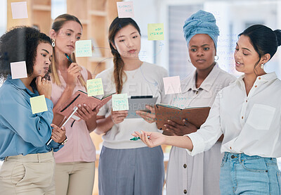 Buy stock photo Female planning, strategy and project management with sticky notes or training in informal business collaboration meeting, discussion or idea sharing. Multicultural women working or organizing