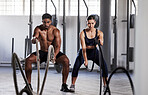 Active, fitness partners training together, exercising with battle ropes in gym. Athletic sports couple in motion doing arms and cardio workout in wellness center for strength and healthy lifestyle.