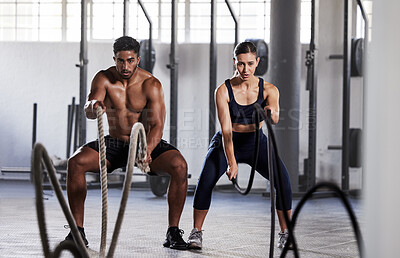 Buy stock photo Active, fitness partners training together, exercising with battle ropes in gym. Athletic sports couple in motion doing arms and cardio workout in wellness center for strength and healthy lifestyle.