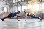 Active couple holding hands for support in pushup, plank and balance training during fitness, workout and exercise in a gym. Sporty, strong and fit athletes helping with bodyweight wellness challenge