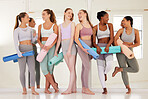 Wellness, friends and yoga by diverse women health club or studio, relaxed and happy. Many females chatting before a session, standing in row with exercise mat before meditation and peaceful zen