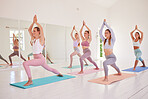 Yoga, class and warrior pose of women exercising and stretching during their morning workout or exercise. Group of calm, fit and active woman training together living a healthy balanced lifestyle.