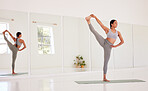 Yoga, fitness and wellness woman doing one leg up pose in a wellness studio with big mirror and copy space. Flexible, athletic and fit woman on an exercise mat while exercising for health and balance
