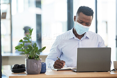 Buy stock photo Covid, mask and business man working in quarantine during a pandemic at the office or workplace for safety. Man alone taking or writing important notes while at work on a laptop and being productive.