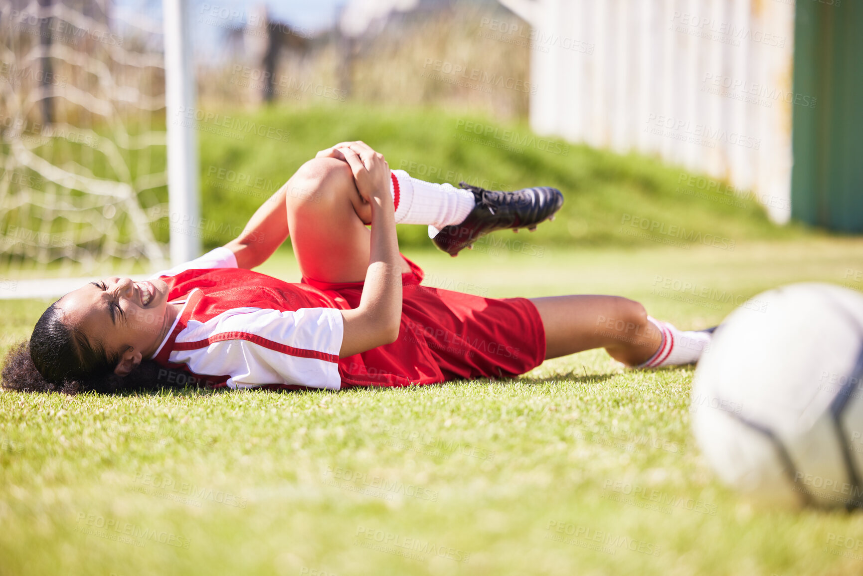 Buy stock photo Injured, pain or injury of a female soccer player lying on a field holding her knee during a match. Hurt woman footballer  with a painful leg on the ground in agony having a bad day on the pitch