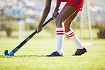 Hockey practice, sports and training with a player hitting a ball with a stick and exercise fitness for a match or sport field event. Strong athlete being active, healthy and fit running outside