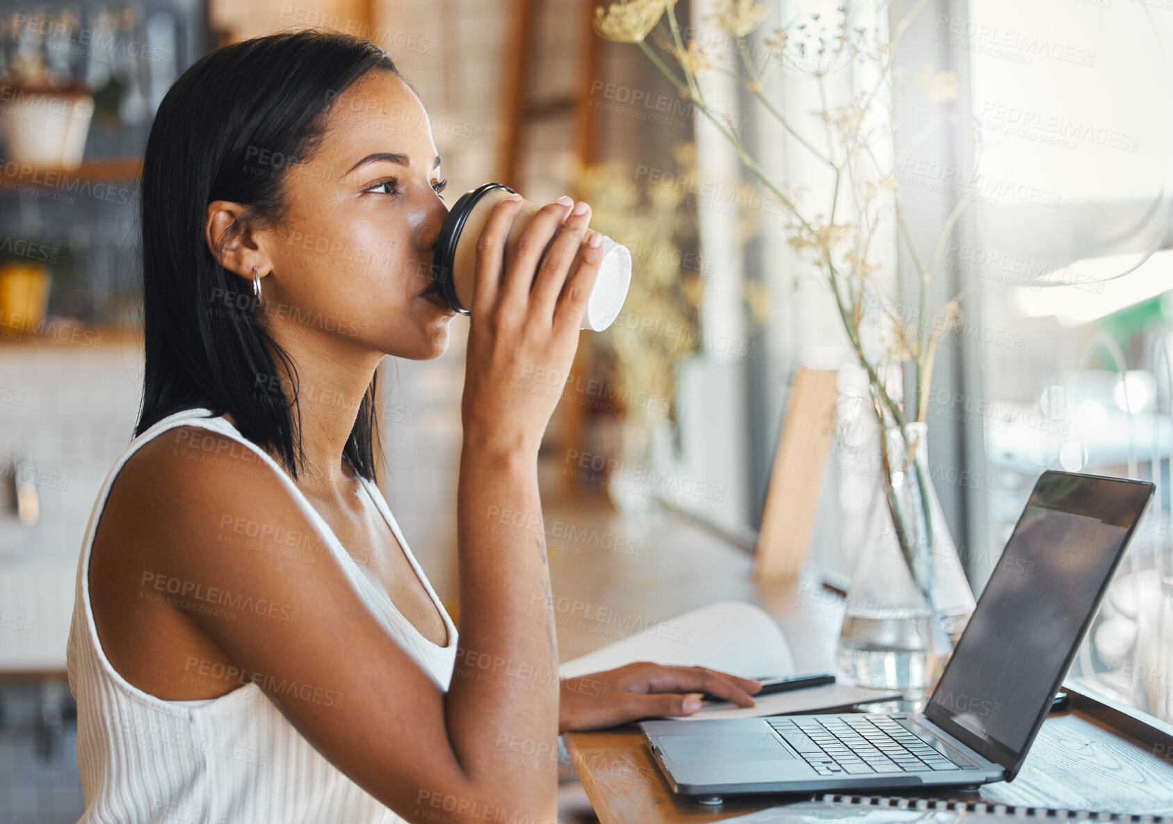 Buy stock photo Young freelance worker drinking coffee and working on a laptop in a cafe. Woman entrepreneur reading work or business email online with technology. Motivated for growth in ecommerce startup company 