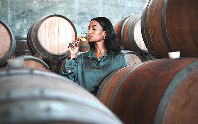 Buy stock photo Woman doing wine tasting, drinking glass of chardonnay or sauvignon blanc in winery cellar amongst barrels on vineyard. Beautiful oenologist or sommelier enjoying a relaxing, luxury beverage indoors.