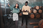 Man, woman and winemaker giving tour to new employee learning logistics in a winery or wood barrel distillery. Business owner or ceo working at alcohol manufacturing and vineyard startup warehouse
