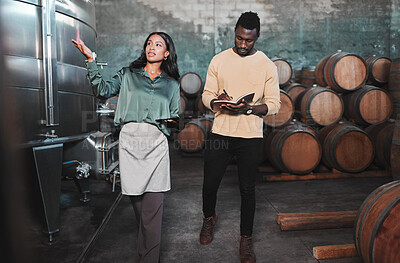 Buy stock photo Man, woman and winemaker giving tour to new employee learning logistics in a winery or wood barrel distillery. Business owner or ceo working at alcohol manufacturing and vineyard startup warehouse
