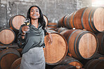 Portrait, woman and winemaker with a glass with wood barrels of white wine in a winery cellar or distillery. Ceo or business owner working for alcohol and vineyard startup, warehouse or factory.


