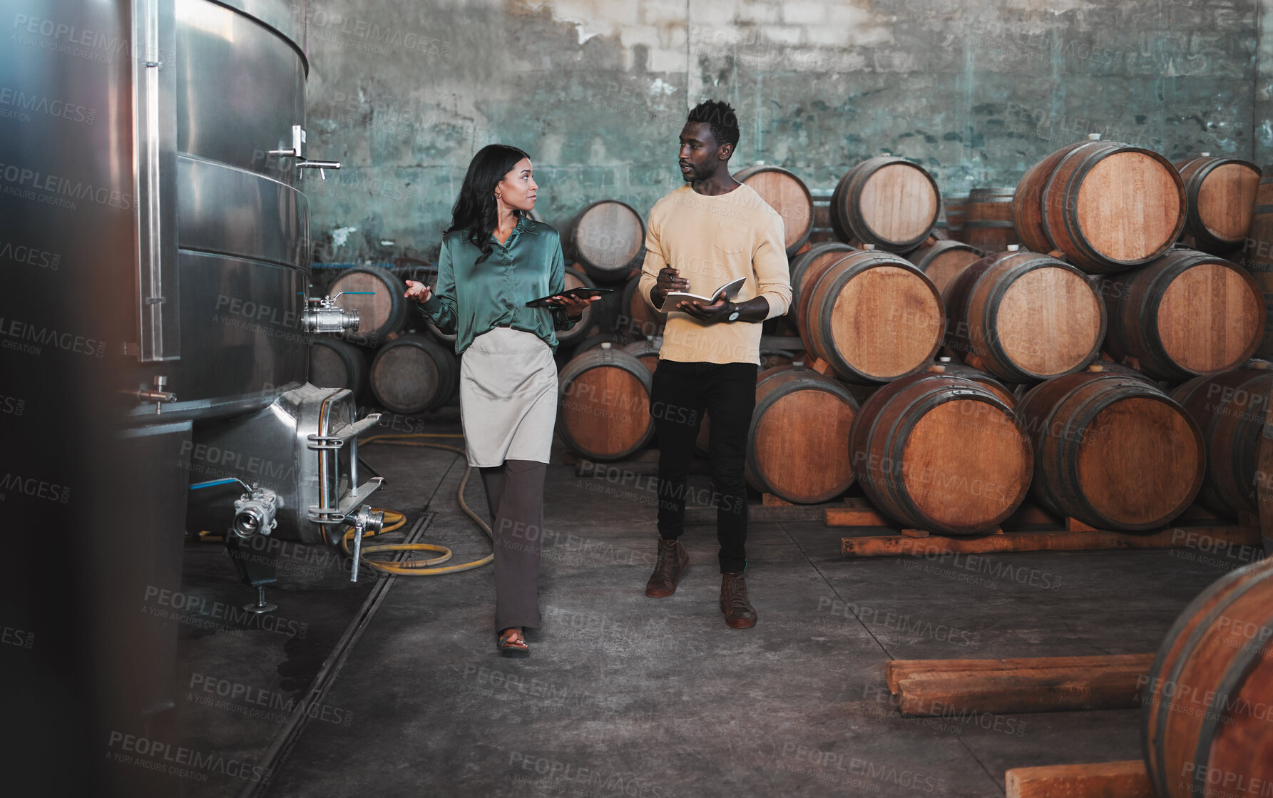 Buy stock photo Wine cellar, warehouse and winery worker teaching a man about wine while he is writing notes. Winemaker walking in a distillery with wooden barrels and agriculture machines while consulting a partner