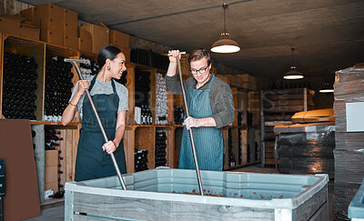 Buy stock photo Winery workers making wine with a fruit press tool or equipment in warehouse or distillery. Woman and man winemakers or factory people pressing juice of grapes manufacturing alcohol for the industry.