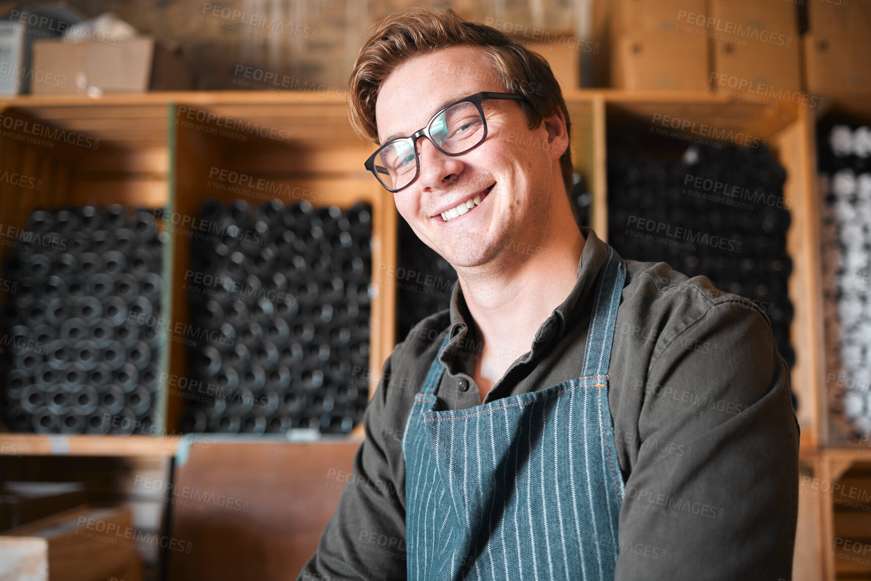 Buy stock photo Happy, smile and proud wine, warehouse or manufacturing worker wearing glasses in a cellar with a bottle collection on display. Winery manager or employee in the alcohol industry or distillery 