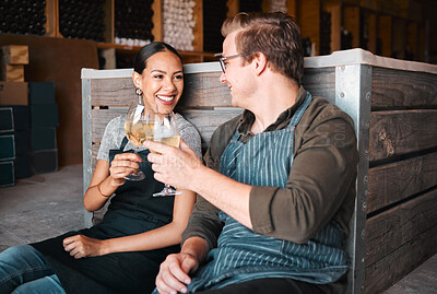 Buy stock photo Successful distillery owners relaxing and celebrating with a glass of wine in the cellar or warehouse. Relaxed winemakers or employees enjoying an alcohol drink together at work