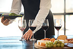 Waiter pouring red wine in wineglass, preparing for a wine tasting at a restaurant with a professional sommelier. Fine dining and good service in the hospitality industry by a male winemaker 