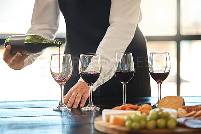 Buy stock photo Luxury, fine dining and hospitality with a waiter pouring red wine at a restaurant. Preparing for a wine tasting with a professional sommelier, good service with quality drink by a male winemaker