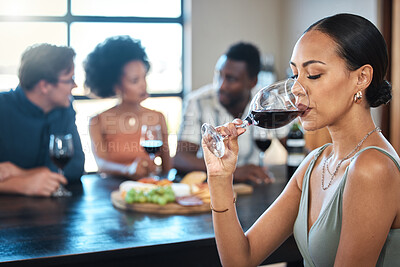Buy stock photo A woman drinking a glass of wine at a dinner table with friends in a restaurant and enjoying the luxury alcohol. Young African American female having fun dining with people at a celebration