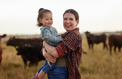 Buy stock photo Family, mother and baby on a farm with cows in the background eating grass, sustainability and agriculture. Happy organic dairy farmer mom with her girl and cattle herd outside in sustainable nature
