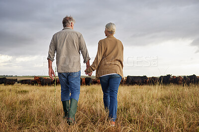Buy stock photo Mature couple holding hands and walking on a cattle farm, bonding and having a stress free day together. Senior farmers enjoying outdoors, being active and loving on romantic walk at sunset