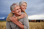 Mature couple embracing and looking happy while bonding outdoors at a farm, carefree and loving. Senior husband and wife talking and having peaceful day in nature, enjoying retirement and relationship