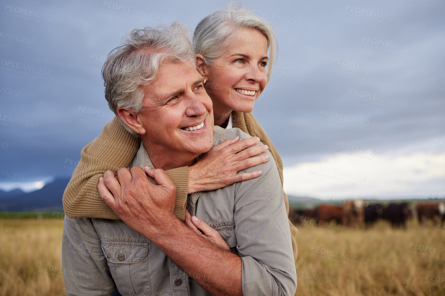 Buy stock photo Mature couple embracing and looking happy while bonding outdoors at a farm, carefree and loving. Senior husband and wife having peaceful day in nature, enjoying retirement and relationship