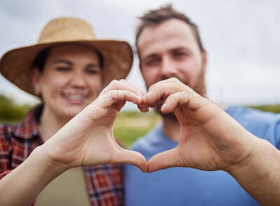 Buy stock photo Farmer couple support sustainability by making a love heart sign with their hands outdoors on an organic farm. Happy and carefree activists with a passion for sustainable and organic farming