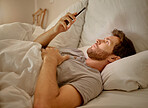 Man in bed at night with phone live streaming on mobile app,  social media content on the internet in his bedroom with home wifi. Person relax with smartphone on digital website or online software