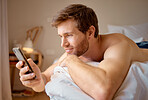 Phone web search, internet streaming and texting of an attractive man relaxing in his bedroom bed. Digital, online and social media content on a 5g mobile while a guy relax at a house with technology
