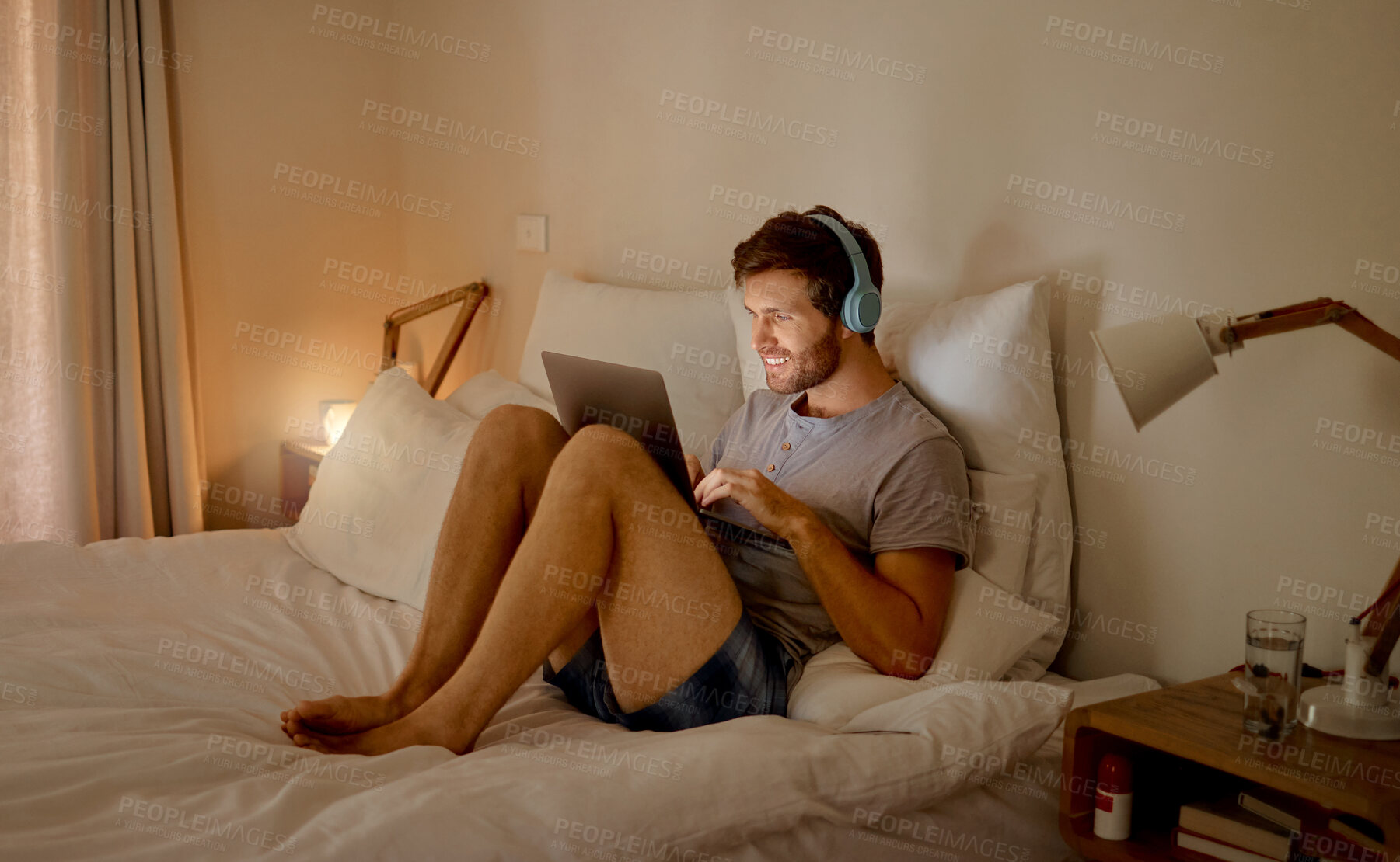 Buy stock photo Laptop, internet and relax with a young man streaming music, video or a podcast online with technology and sitting on his bed in the bedroom at home. Enjoying freedom, tech and radio during free time