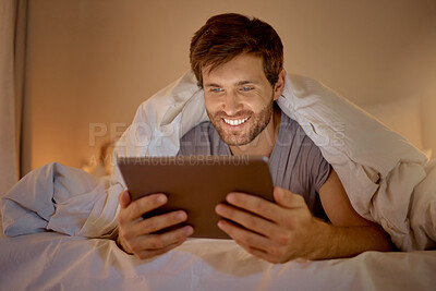 Buy stock photo Happy man relaxing in bed with digital tablet watch, movie, series or online social media videos on an app. Browsing the internet news with 5g technology on wireless device in the bedroom at home