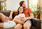 Happy, love and interracial couple smile looking away relax and sitting on a couch at home. Diversity man and woman smiling and enjoying quality relationship together and having romance in the house