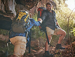 Nature, fitness and hiking men climbing up rocks on a mountain hike trail during spring. Fit man holding a friend's hand to help him walk up stones with a backpack on an adventure health workout.