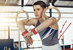 Fitness, exercise man in gymnastics gym during practice, training or exercise on rings and taking a break. Young sports athlete or gymnast calm and thinking of workout idea to improve skill or cardio
