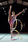 Rhythmic gymnastics, fitness and sports girl performing a professional routine with a ribbon in arena. Portrait of woman athlete training balance, strength and flexibility exercise for a competition.