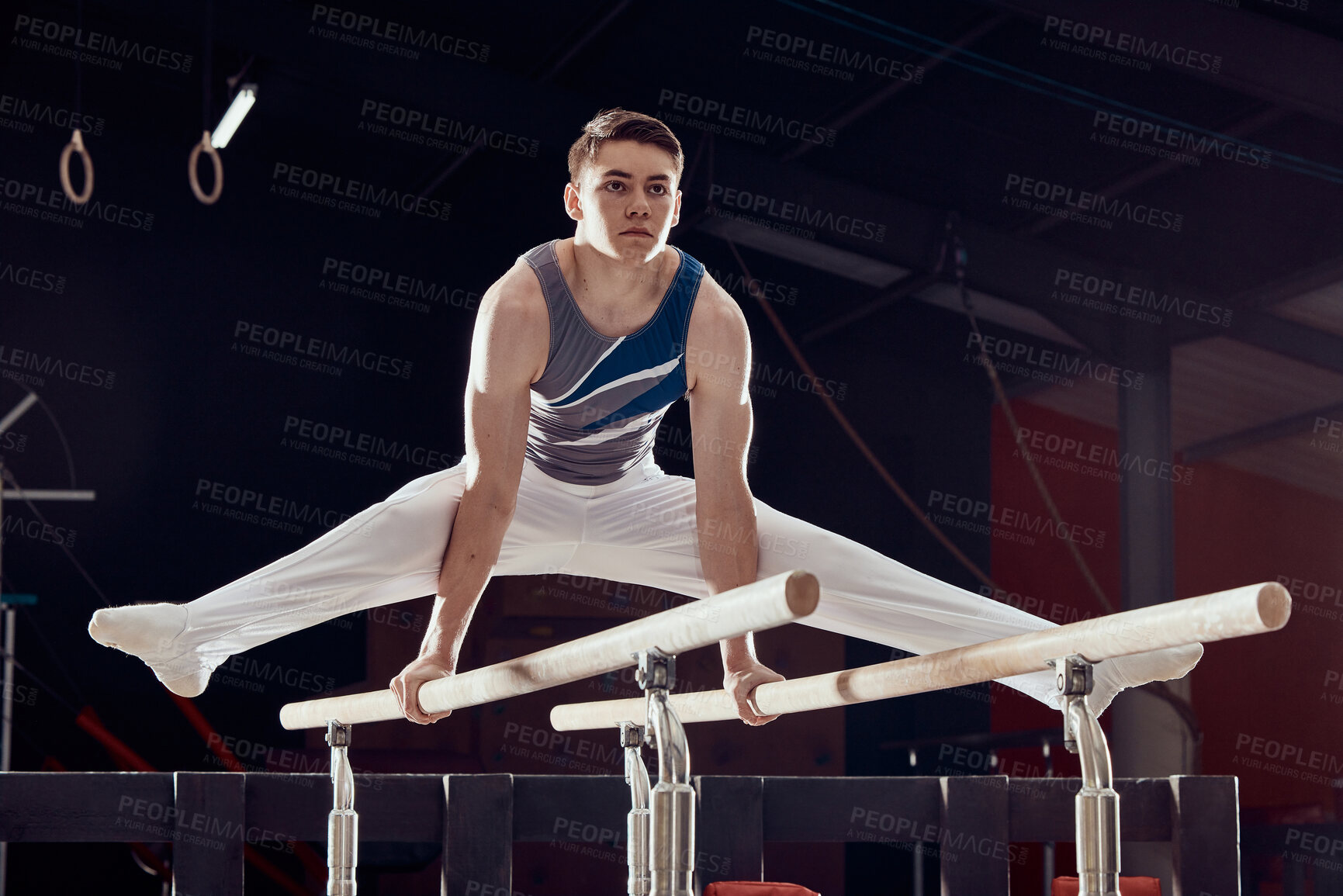 Buy stock photo Gym, man and training for balance and fitness in professional gymnastics for cardio sports workout at night. Young athletic guy in dark competitive acrobat exercise in sport practice for competition.