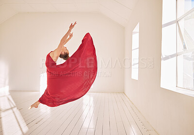 Buy stock photo Woman, ballet and dance of a girl student dancing in a red dress in a studio mockup with white walls and sunlight. Young professional female ballerina, art or dancer jumping in the air in a class.