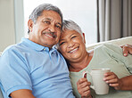 Portrait of a senior couple sitting on sofa in the living room while hugging and smiling. Care, love and happy mature woman and man embracing each other while having tea and relaxing on couch at home