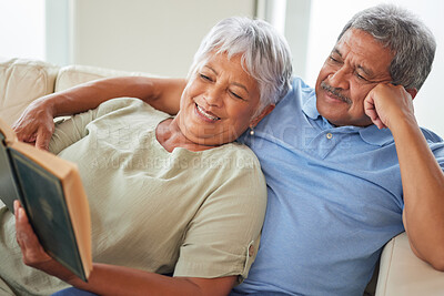 Buy stock photo Relax, happy and senior couple reading a book together at home while relaxing and smiling on a couch. Mature or old lovers learning and resting while enjoying a story as entertainment in the house