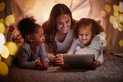 Buy stock photo Mother and children live streaming on an app using a tablet in a tent camping at home at night. Happy mom and kids watching online content or playing games with house wifi in the dark or evening