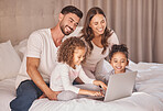 Family, laptop and relax on bed together with kids for bonding time. Caring home, parents and young daughters with happy relationship. Smiling couple and children having quality time while relaxing.