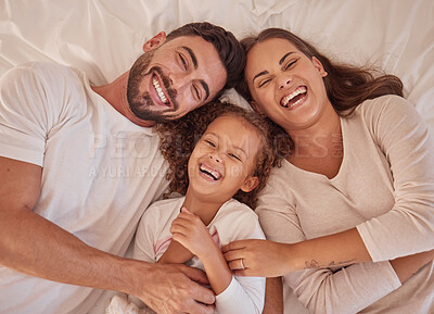 Buy stock photo Happy family, girl and laughing parents having fun and spending quality time together at home from above. Portrait of funny mother, father lying with their child and sharing love in their bedroom